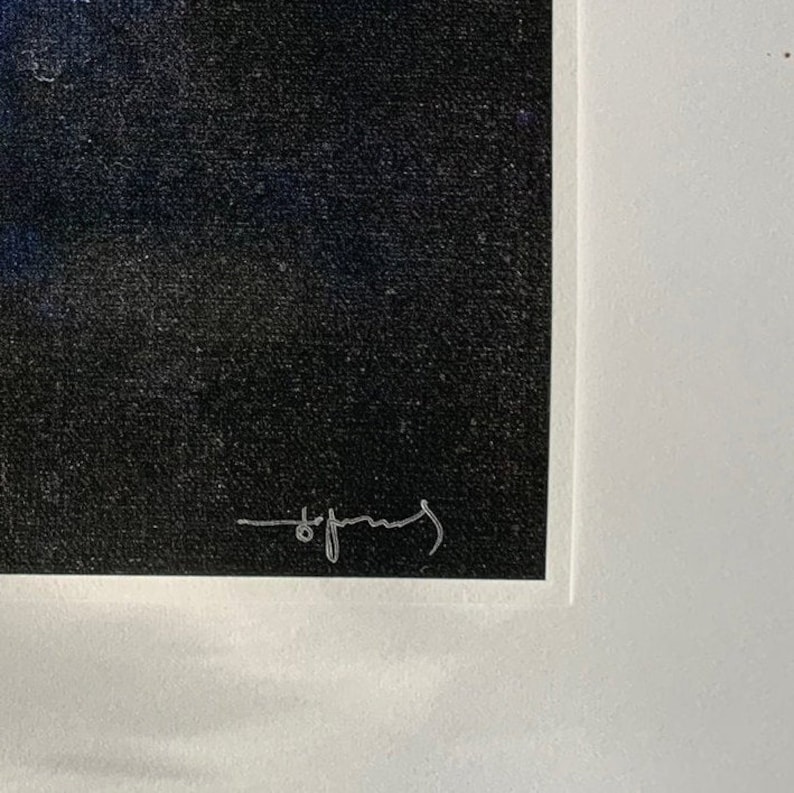 A detail of a brushed tricorn black background with the author's hand signed signature in a white pass-par-tout (mount).