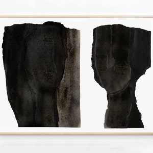 A maple wood framed, high quality art print of a modern abstract double portrait in asphalt black and dark brown on white, composed of a torn paper layers with grungy edges. The texture has a water color effect. Shades of tan browns remind of a nose.