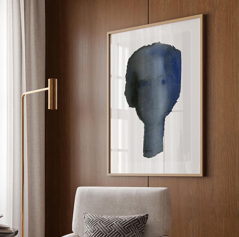 Puede incluir: Una pintura abstracta de acuarela enmarcada de una cara azul y gris sobre un fondo blanco.