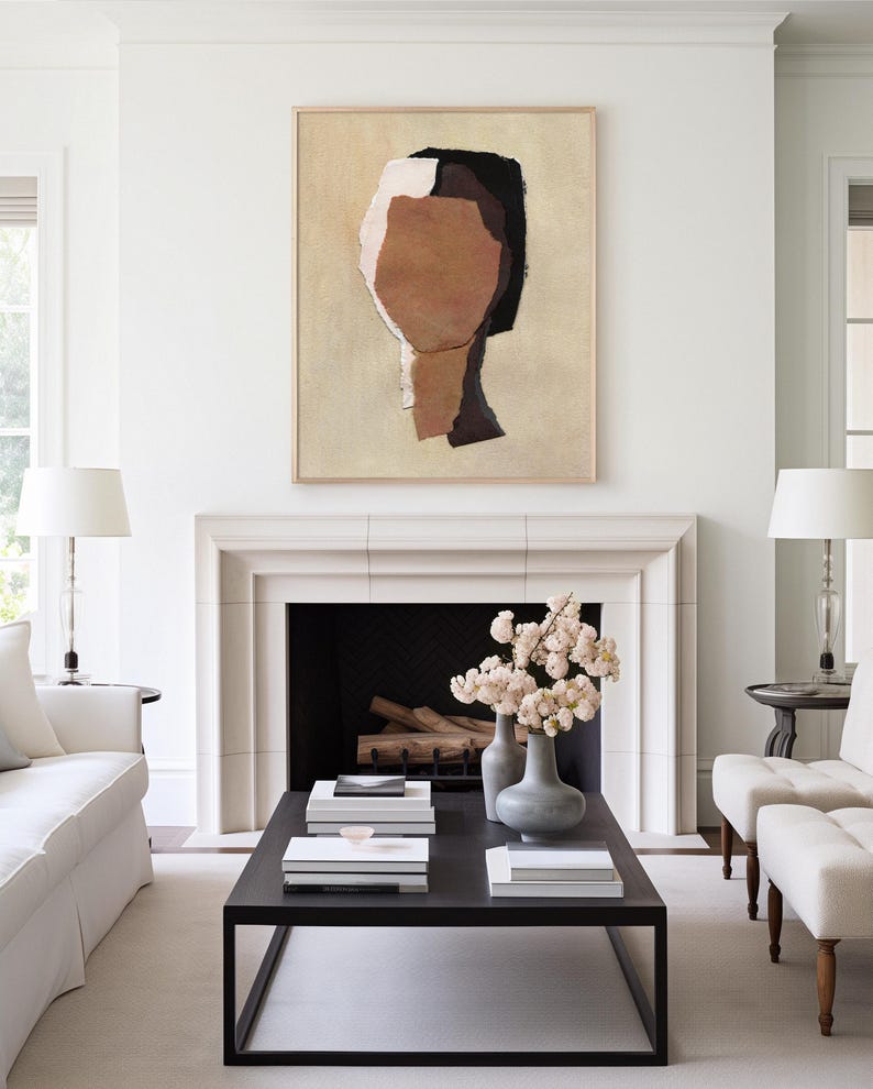 May include: Abstract art piece featuring a neutral color palette. The artwork, in a wooden frame, depicts a stylized human form with shades of brown, black, and white. The painting hangs above a fireplace, complementing the room's minimalist decor.