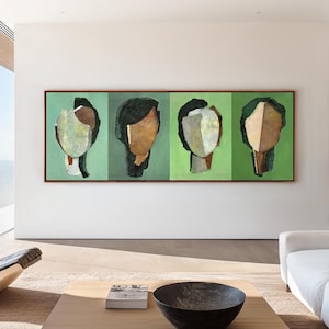 Può includere: Dipinto astratto con quattro volti stilizzati in tonalità di marrone, verde e bianco. Il dipinto è incorniciato in una cornice di legno scuro e appeso a una parete bianca.