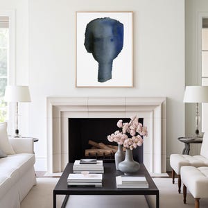 Puede incluir: Una habitaci&oacute;n blanca con una chimenea y una mesa de caf&eacute; negra. La chimenea tiene un hogar negro y una repisa blanca. Hay dos sillones blancos y un sof&aacute; blanco en la habitaci&oacute;n. Una pintura de acuarela enmarcada de una cara azul cuelga sobre la chimenea.