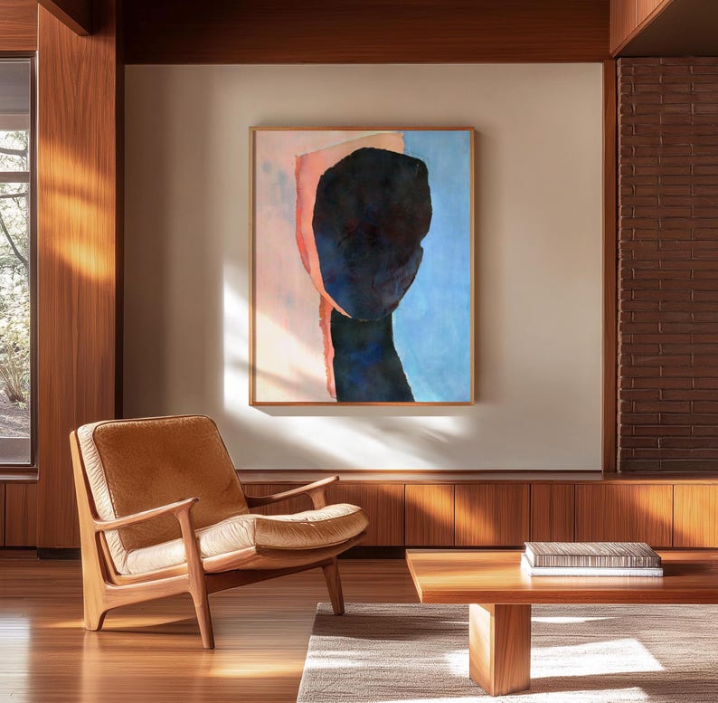 K&ouml;nnte beinhalten: Ein Wohnzimmer im Stil der Mid-Century Modern mit einem braunen Ledersessel, einem Holz-Couchtisch und einem gerahmten abstrakten Gem&auml;lde eines blauen und rosafarbenen Gesichts an der Wand.