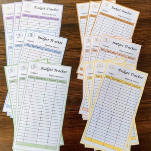 Puede incluir: Una pila de hojas de seguimiento de presupuesto imprimibles en varios colores, incluidos amarillo, verde, azul y naranja. Cada hoja tiene un título que dice "Budget Tracker" e incluye columnas para categoría, fecha, descripción, cantidad y saldo.