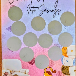 May include: A colorful card with the text "Crochet Away Into Savings" and a $50 value. The card features a white armchair, a basket of yarn, and a playful cat with a ball of yarn. There are 12 scratch-off circles.