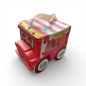 May include: A vintage pink and white toy beach buggy with a handle. The buggy has a striped roof, round wheels, and the words "Beach Buggy" printed on the side. The buggy has a handle and is decorated with illustrations.
