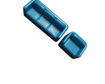 May include: Two turquoise plastic trays, one rectangular with three compartments and one square. The trays are empty and have a textured surface. The items are set against a white background.