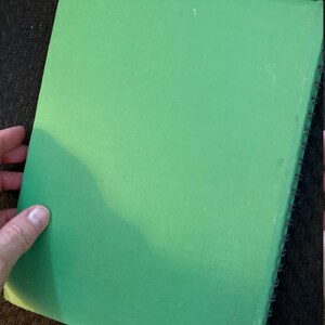 May include: A green spiral bound notebook with a plain cover.
