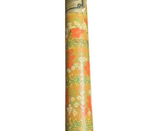 May include: A rolled-up roll of floral wrapping paper. The paper has a yellow background with a pattern of orange flowers, white daisies, and green leaves. A label is visible on the roll with text in English and French.