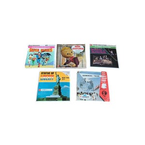 May include: A collection of vintage View-Master reels. The reels feature colorful covers with titles like "Super Heroes," "Bebe Antoine," and "Statue of Liberty." The reels are rectangular and have a retro aesthetic.