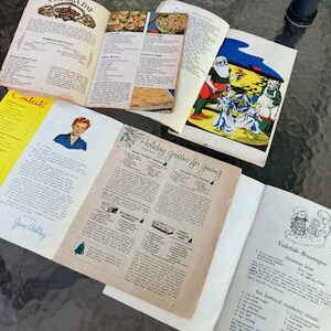 May include: Open vintage cookbooks with recipes for Victoria Day and holiday treats. One page features a Santa Claus illustration. The text includes "Holiday goodies for giving" and "Yuletide Beverages".