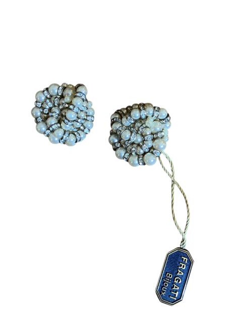 Puede incluir: Dos pendientes redondos con cuentas de aspecto perlado y detalles de pedrer&iacute;a. Los pendientes tienen un dise&ntilde;o agrupado. Una etiqueta azul con el texto "FRAGATI Bijoux" est&aacute; sujeta a uno de los pendientes.