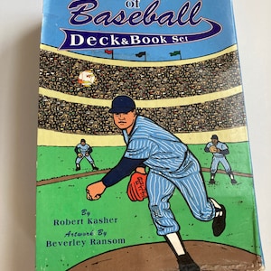 May include: A box for a Tarot of Baseball Deck & Book Set. The box features a cartoon illustration of a baseball player pitching in a stadium. The text on the box reads "Tarot of Baseball Deck & Book Set" and includes the names of the author and illustrator: "By Robert Kasher Artwork By Beverley Ransom".