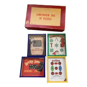 May include: A vintage wooden box of puzzles with the text "Compendium Box of Puzzles" on the lid. The box contains four smaller boxes with different puzzles, including "The Lucky Seven Domino Puzzle", "The Divers Puzzle", and "Geometrical Puzzle".