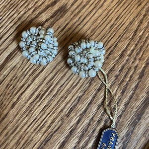 Puede incluir: Un par de pendientes vintage de clip con dise&ntilde;o de racimo. Cada pendiente presenta perlas de imitaci&oacute;n y pedrer&iacute;a transparente. Una etiqueta con el texto "FRAGATI Bijoux" est&aacute; adjunta.