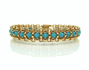 May include: A gold chain bracelet with turquoise blue beads. The bracelet is made of a delicate chain with a row of turquoise blue beads in the centre.