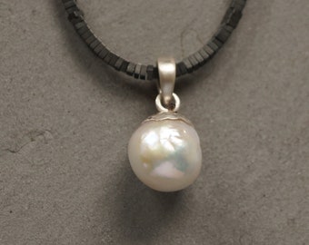 Large white pearl on a black chain with silver