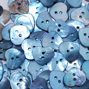 Può includere: Una collezione di bottoni a forma di cuore blu iridescente. I bottoni hanno due fori ciascuno e sono realizzati in un materiale liscio e lucido.