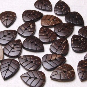 May include: A collection of brown coconut shell buttons shaped like leaves. Each button has two holes and a natural wood grain pattern.