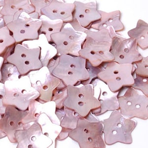 May include: A pile of pink, star-shaped buttons made from mother of pearl. The buttons have two holes each.