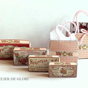 Puede incluir: Cinco cajas en miniatura con diseños florales vintage. Las cajas son de color rosa, rojo y blanco con detalles dorados. Las cajas están etiquetadas con las palabras "Roses Merveilleuses", "Savon a la Rose", "Rosenkreef" y "Savon Ala Rose".