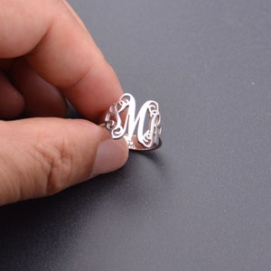 Peut inclure: Une bague en argent avec un motif d&eacute;licat et orn&eacute; repr&eacute;sentant la lettre "M".
