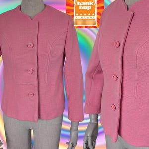May include: A vintage pink jacket with a textured weave, featuring a round collar and three buttons. The jacket has long sleeves and a tailored fit, displayed on a mannequin. The "Tank Top Vintage" logo is visible in the background.
