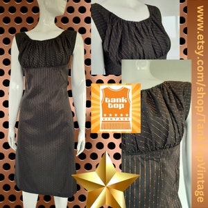 Peut inclure: Une robe sans manches noire et orange à rayures avec un col plissé. La robe est faite d'un tissu léger et a une silhouette ajustée.