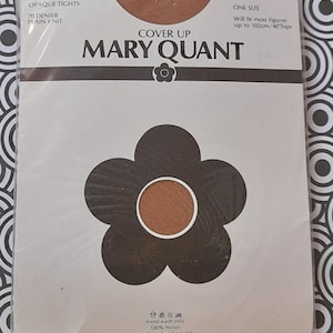 Könnte beinhalten: Eine braune Packung mit Mary Quant blickdichten Strumpfhosen. Die Packung zeigt eine große braune Margerite mit schwarzem Umriss. Der Text auf der Packung lautet "Cover Up Mary Quant", "Opaque Tights", "70 Denier Plain Knit", "One Size", "Will fit most figures up to 102cm/40 hips", "Hand wash only 100% Nylon NHC/Made in England".