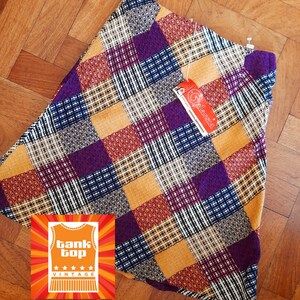 May include: A vintage patchwork skirt with a vibrant mix of colors including purple, gold, navy, and burgundy. The skirt features a variety of geometric patterns and textures. A tag with the brand name "Glarissa" is attached. A "Tank Top Vintage" logo is visible.