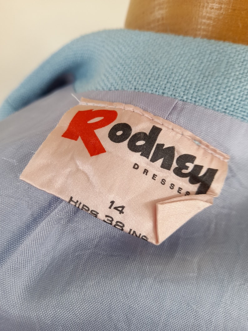 May include: A light blue dress with a pink label that says "Rodney Dresses" and "Hips 38 in 14".
