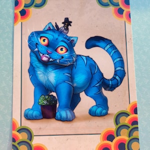 Può includere: Una stampa artistica rettangolare raffigurante un gatto blu brillante con grandi occhi gialli e un sorriso sdentato. Il gatto ha strisce blu scuro, un piccolo cappello nero sulla testa e si trova accanto a una piccola pianta in vaso. Il bordo presenta cerchi concentrici colorati.