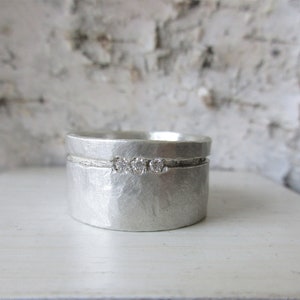 Peut inclure: Une bague en argent avec une finition martelée et trois petits diamants sertis en ligne.
