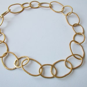 May include: A gold chain necklace made of large, oval-shaped links.