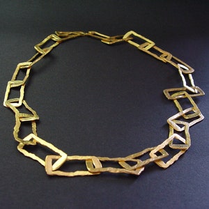 May include: A gold necklace made of linked, rectangular shapes.
