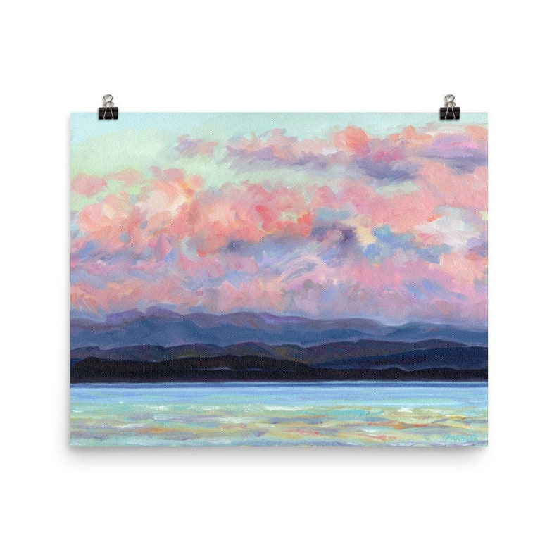 May include: A painting of a pink and blue sunset over a dark blue mountain range and a body of water. The sky is filled with fluffy clouds.