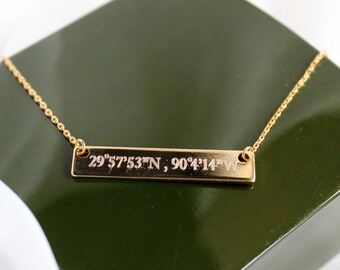 Op de afbeelding: Gouden ketting met een rechthoekige hanger gegraveerd met de coördinaten "29°57'53"N, 90°4'14"W".