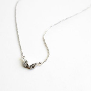 May include: A silver chain necklace with a delicate wing pendant.