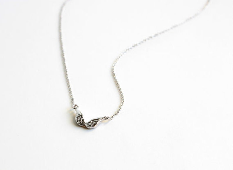 May include: A silver chain necklace with a delicate wing pendant.