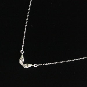 May include: A silver chain necklace with a small wing pendant.