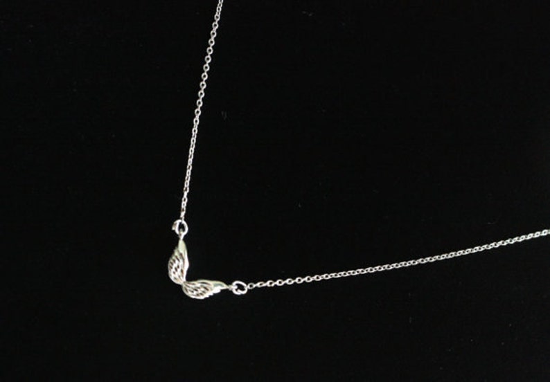 May include: A silver chain necklace with a small wing pendant.