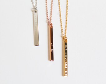 Op de afbeelding: Drie gouden bar kettingen met verschillende gravuren. De kettingen zijn zilver, rosé goud en goud. De gravuren zijn Romeinse cijfers, cijfers en letters.
