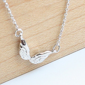 May include: A silver chain necklace with a delicate angel wing pendant.