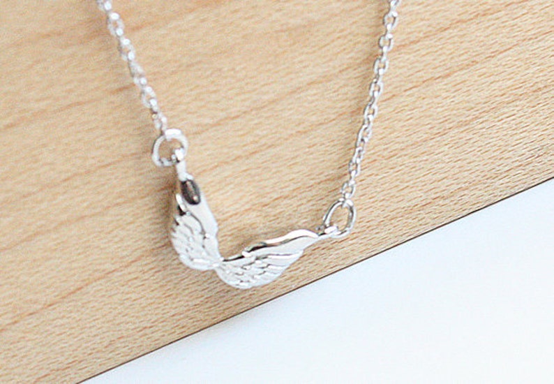 May include: A silver chain necklace with a delicate angel wing pendant.