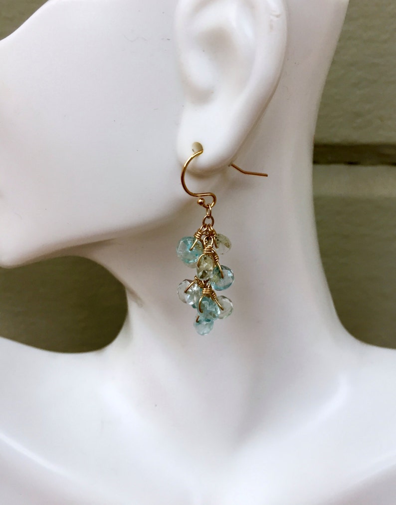 May include: Gold dangle earrings with light blue and green gemstone beads.