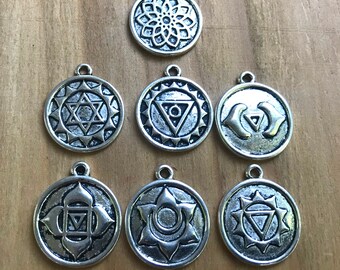 May include: Seven silver charm pendants with different chakra symbols. Each pendant features a unique design with intricate details. The pendants are perfect for jewelry making or adding a touch of spirituality to your home decor.