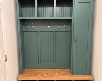 Puede incluir: Un mueble recibidor de color verde azulado con un banco de madera natural, tres compartimentos superiores, seis ganchos para abrigos en tono latón y un armario lateral alto con un tirador de latón a juego. Incluye ocho huecos para zapatos.
