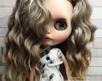 May include: A doll with long, wavy, light brown hair with blonde highlights. The doll is wearing a white dress with a black and white musical note pattern. The doll's eyes are green and she is looking to the side. The text "navy blue navel natural ombre beige angora mohair" is written on the bottom right of the image. The text "Navy Blue Navel" is written in a blue box on the bottom right of the image.