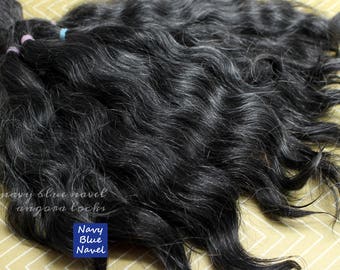 May include: A bundle of black and grey wavy human hair extensions. The hair is soft and silky, and it has a natural, slightly textured look.