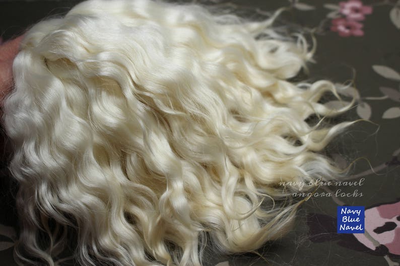 May include: A large quantity of white curly angora wool. The wool is soft and fluffy, and it is ideal for knitting or crocheting.